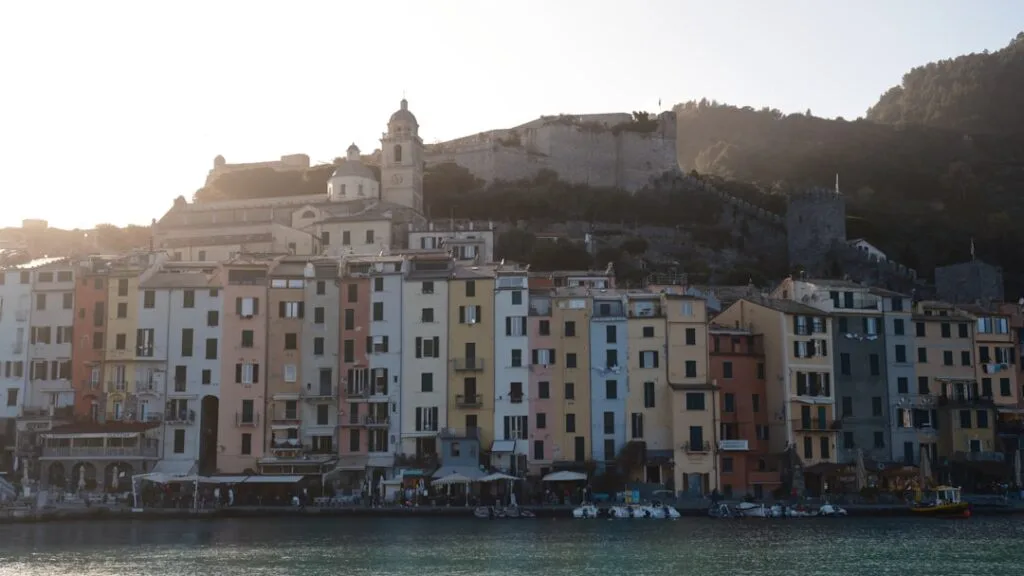 Kleurrijke gevels langs de waterkant in Cinque Terre, met fort op heuvel