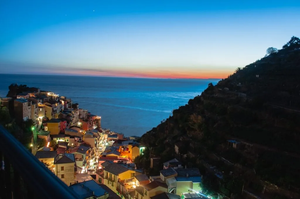 Village côtier illuminé de Cinque Terre au crépuscule, mer calme à l'horizon