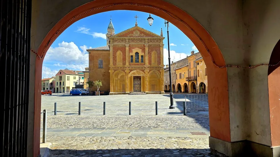Arcade encadre une église jaune sur une place pavée