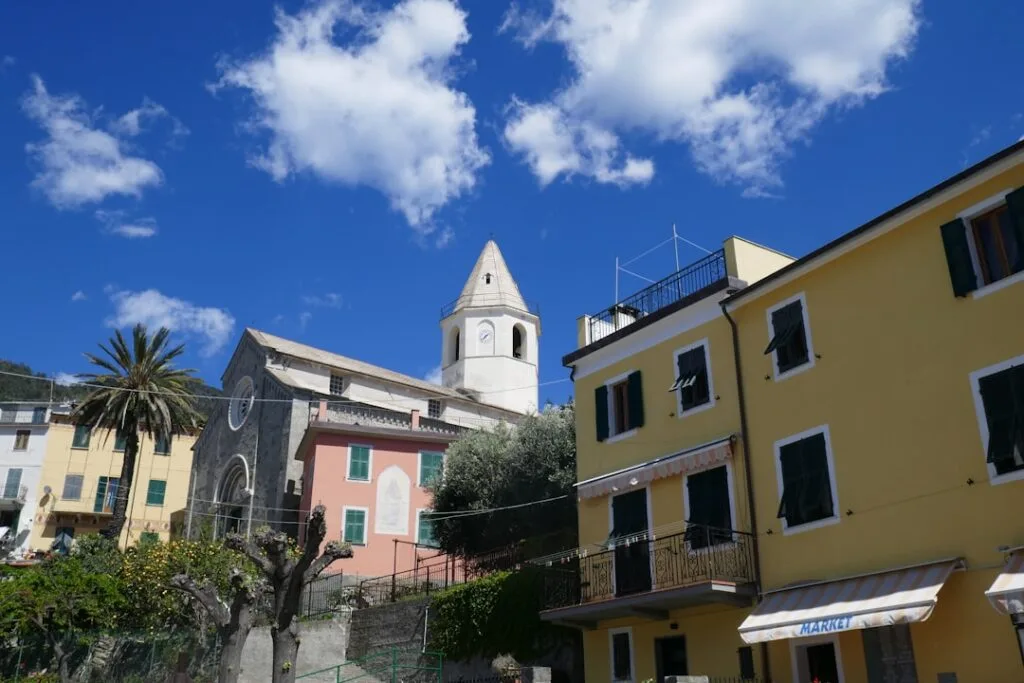 Église et maisons colorées d'un village des Cinque Terre sous ciel bleu
