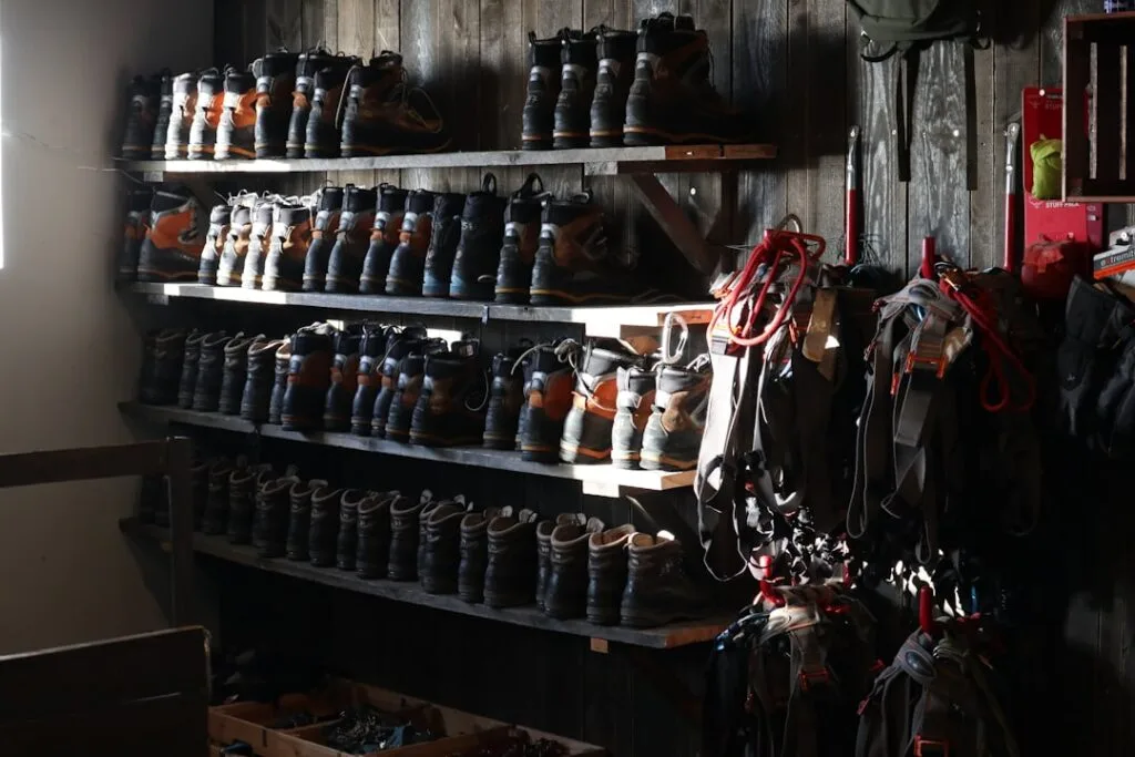 Étagères remplies de bottes de randonnée et de baudriers, éclairage tamisé