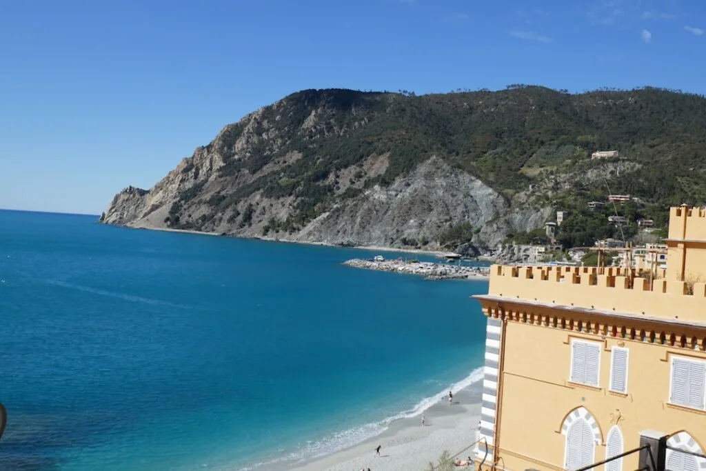 Turquoise zee, klein kiezelstrand en geel gebouw in Cinque Terre