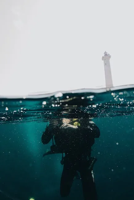 Plongeur mi-submergé dans l'eau, phare visible au-dessus près des Cinque Terre