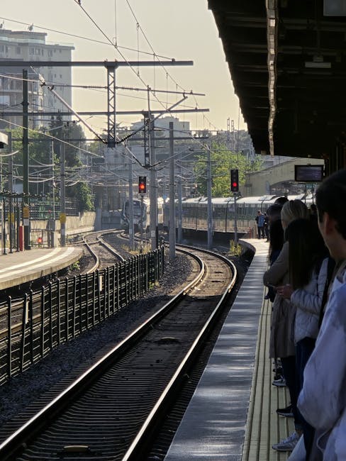 Crowded Italian train platform with commuters waiting beside curving tracks.