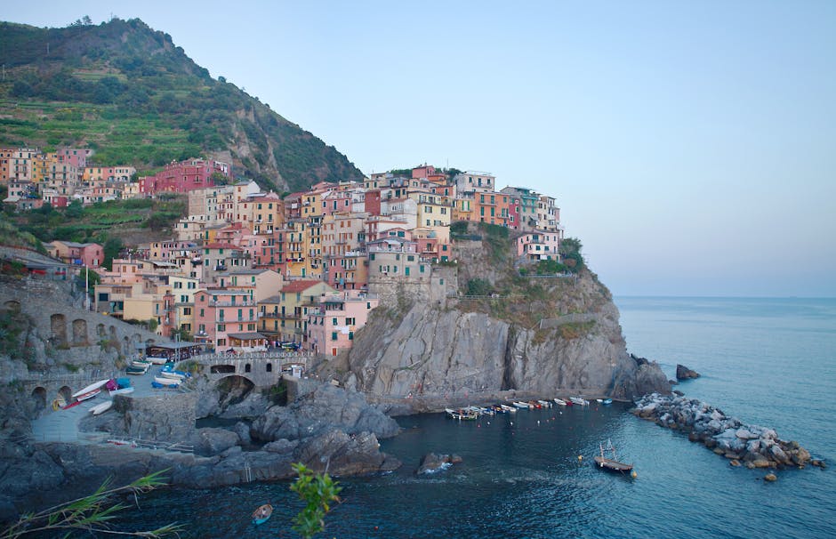 Colorful cliffside houses above a rocky harbor in Cinque Terre