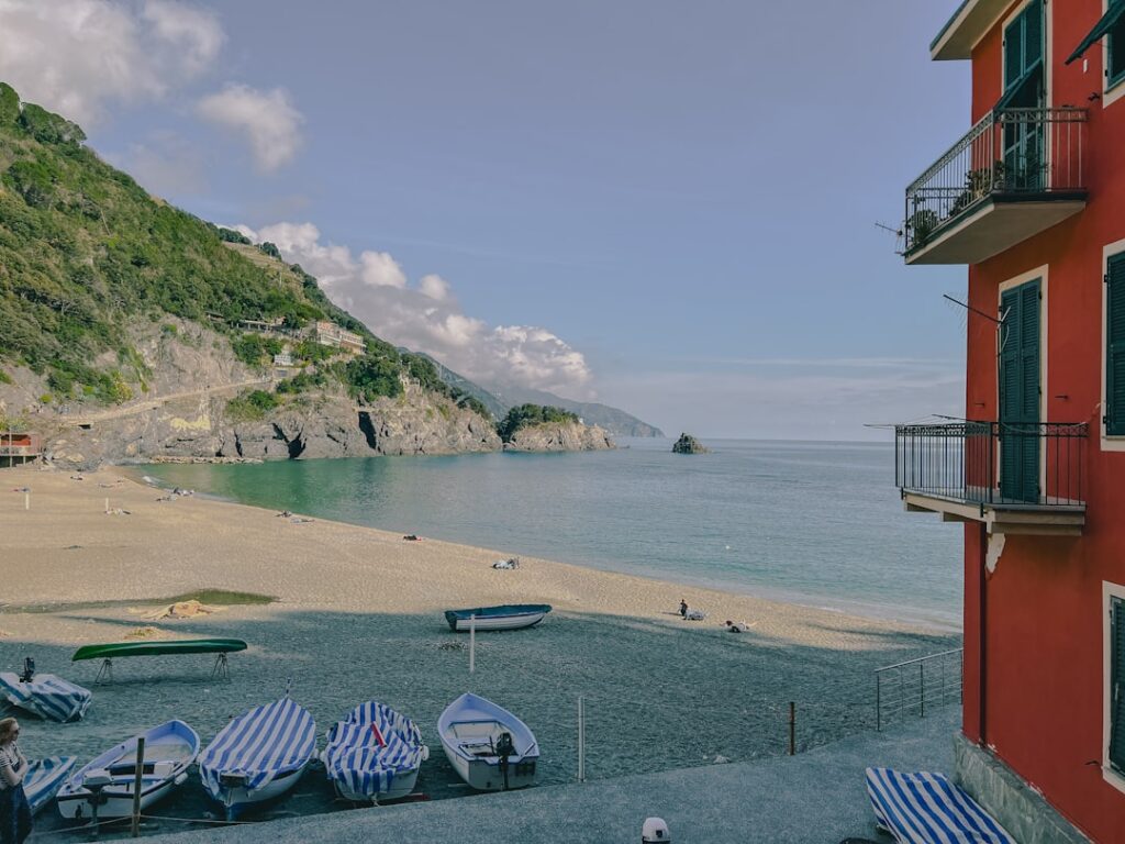 Sandy beach with moored boats and red building in Cinque Terre
