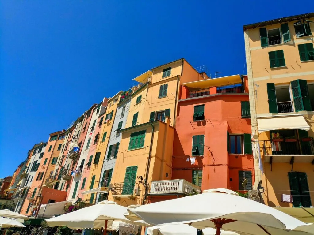 Façades colorées aux volets verts surplombant parasols à Cinque Terre