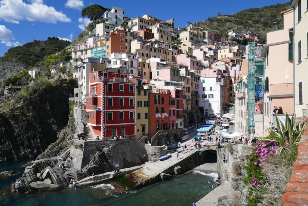 Cluster of pastel buildings and busy harbor walkway in Cinque Terre