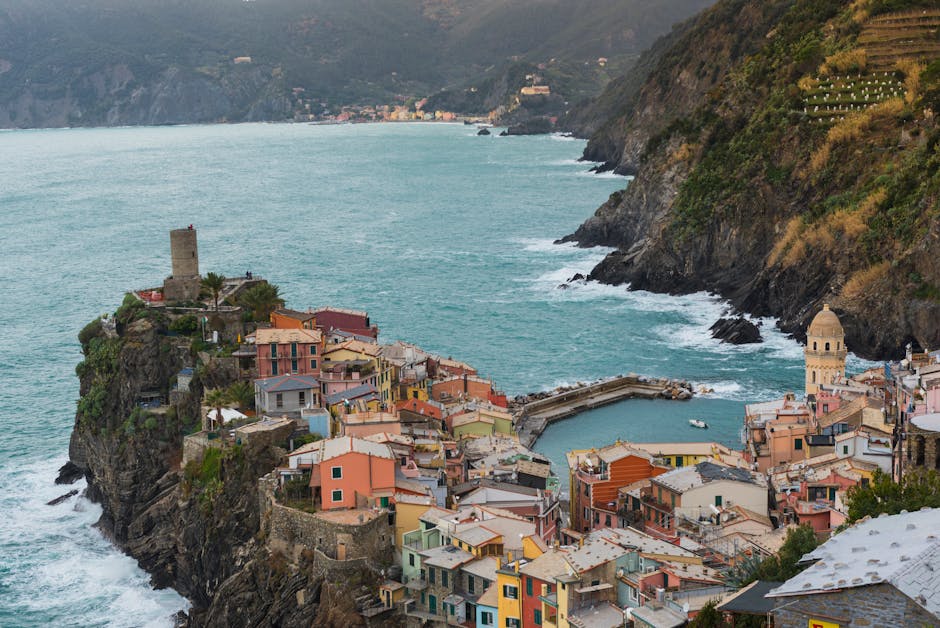 Aerial view of Vernazza harbor and pastel houses on promontory.