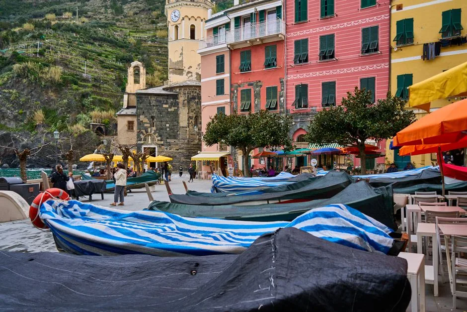 Bedekte boten op voorplein voor kleurrijke gevels en kerk in Cinque Terre