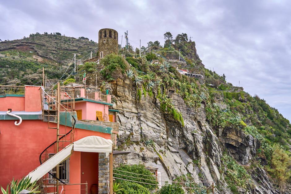 Maison rose au pied d'une tour ronde sur la falaise de Cinque Terre