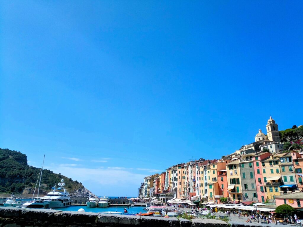 Colorful Cinque Terre harbor buildings with yachts and sunlit promenade