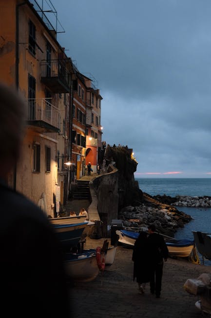 Evening walkway in Cinque Terre with moored boats and silhouetted people