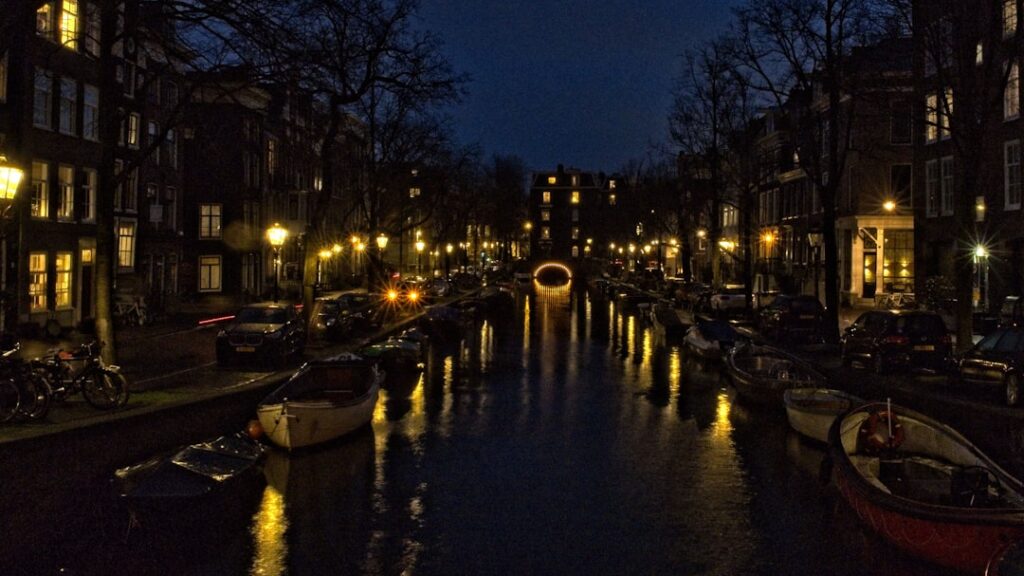 Grachtenpanden in Amsterdam tijdens het gouden uur met reflecties op het water
