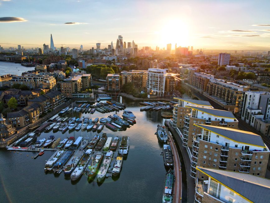 Sunset over the Thames with an empty riverside bench and the London skyline