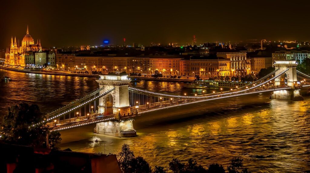 Tram crossing the Chain Bridge with reflections on the Danube at night