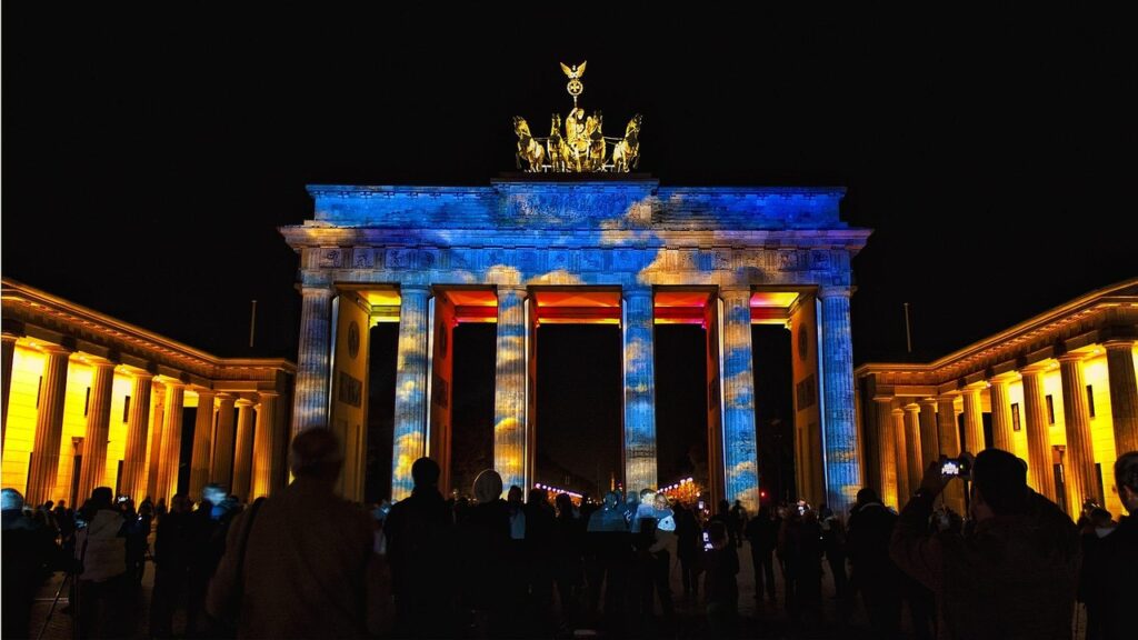 Brandenburg Gate illuminated during the Festival of Lights with pedestrians