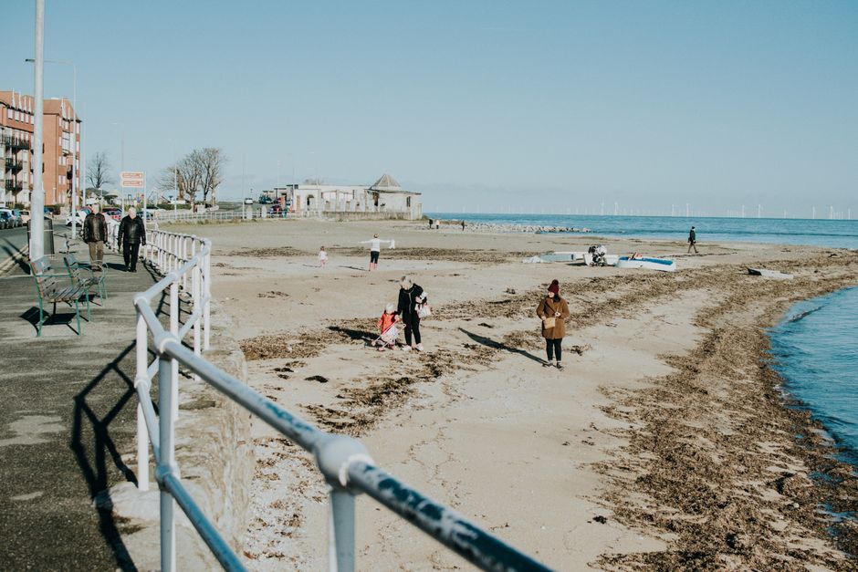 Familien spazieren an einem sonnigen Tag entlang der Promenade von Portobello Beach