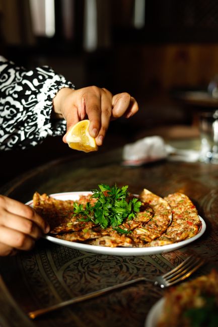 Lahmacun wird mit Zitrone und Petersilie gerollt