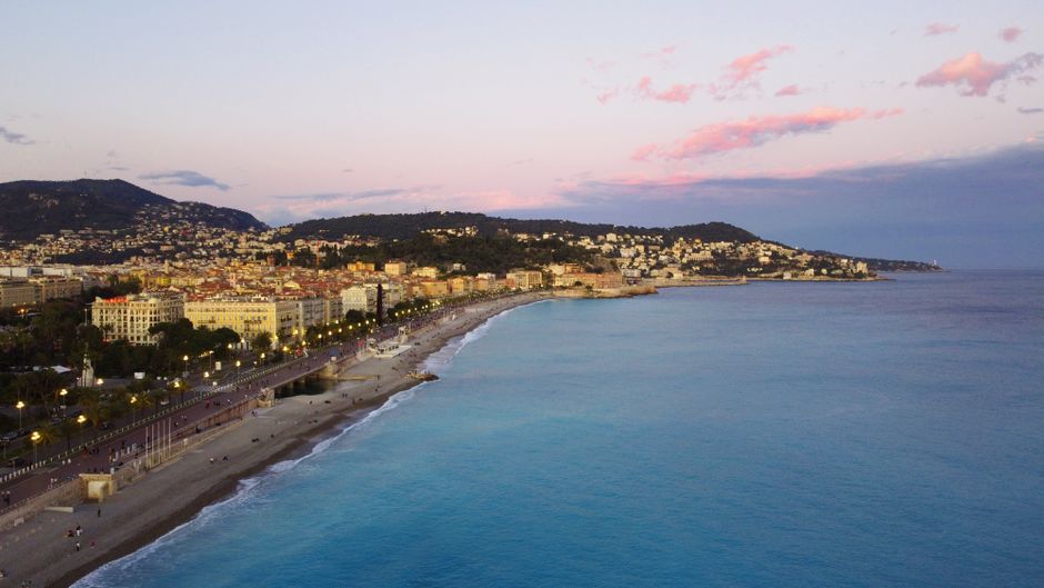 Koppel dat op de Promenade des Anglais wandelt bij zonsondergang