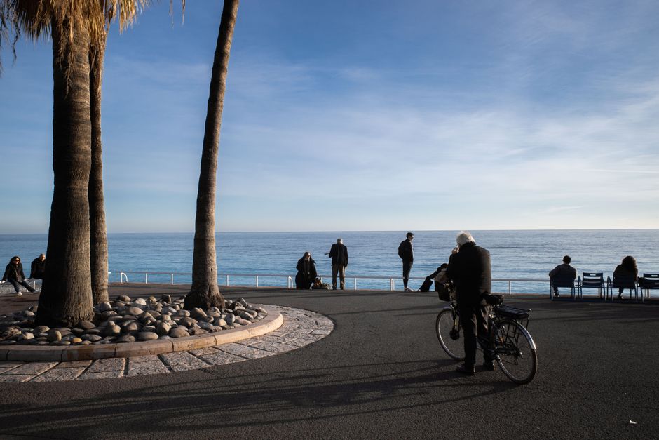 Fietsers en wandelaars langs de boulevard met helderblauwe zee