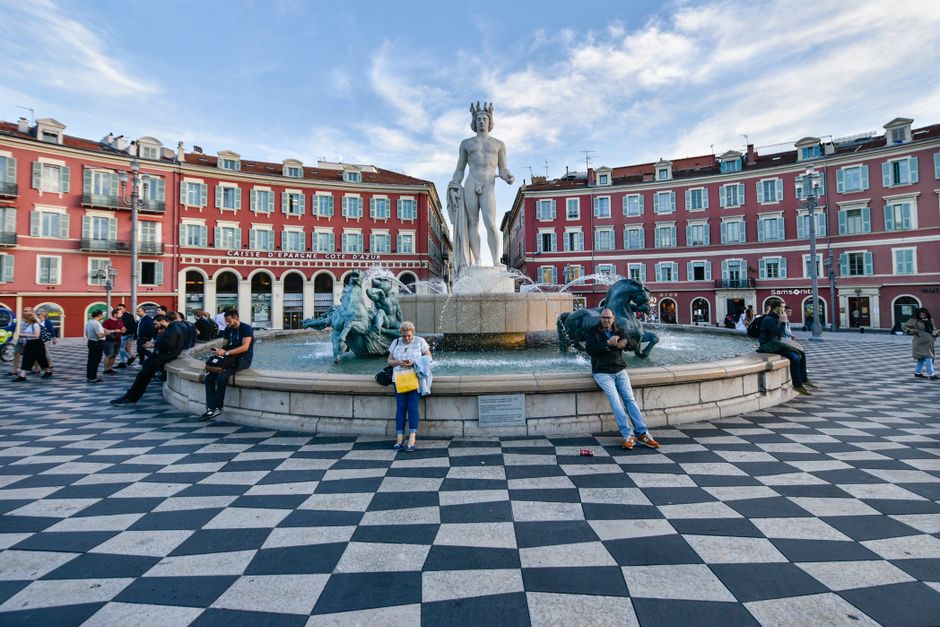 Place Masséna bij avond met verlichte rode gevels en fonteinen