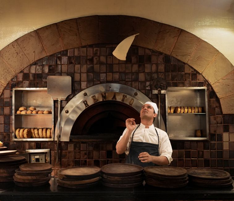 Chef che estrae la socca da un grande forno rotondo in una trattoria tradizionale