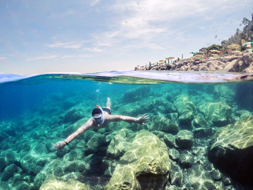 Snorkeler exploring rocky underwater terrain at Cap Rognoso