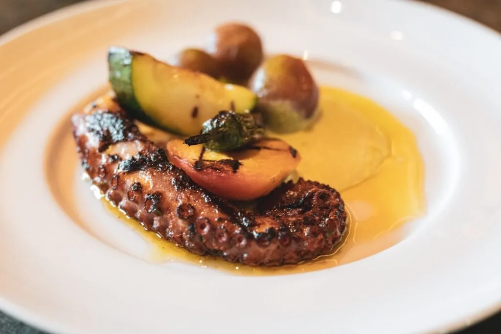 Grillowana macka ośmiornicy podana z grillowanymi warzywami i oliwą