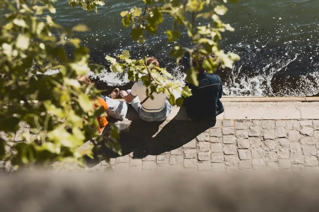 Na kamiennym nabrzeżu rzeki Arno w Pizie siedzą trzy osoby