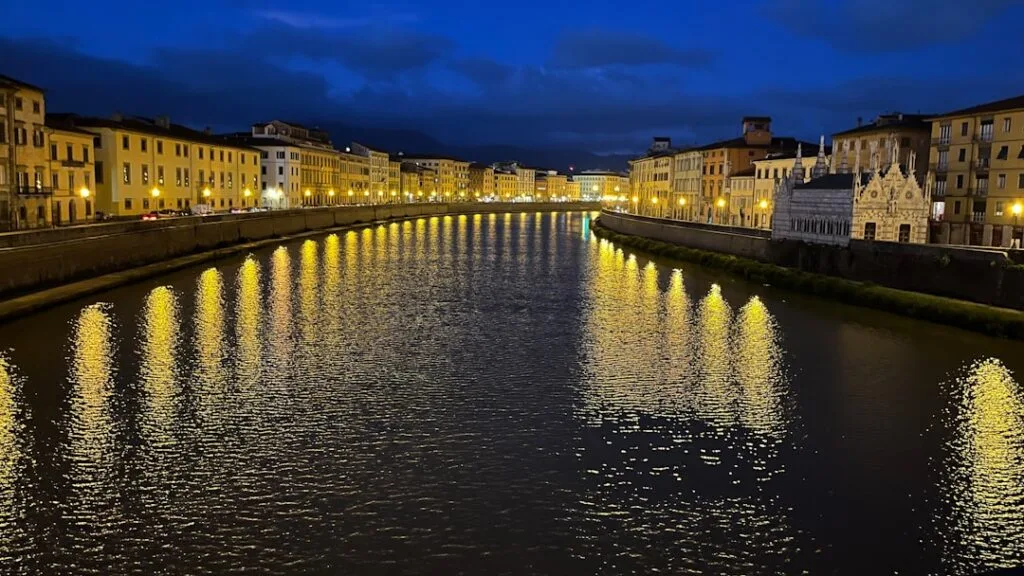 Nocne oświetlenie nabrzeża i odbicia w Arno w Pizie.