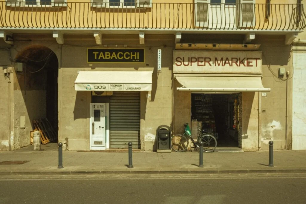 Fasada sklepu TABACCHI i supermarketu z rowerem przed wejściem w Pizie