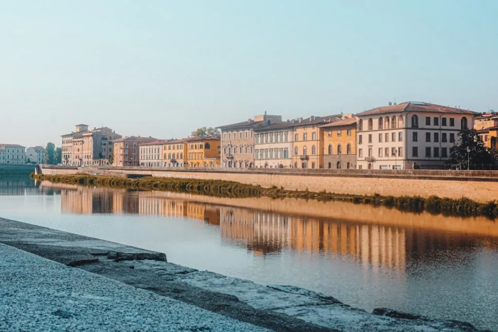 Façades colorées le long de l'Arno à Pise, reflet doré sur l'eau