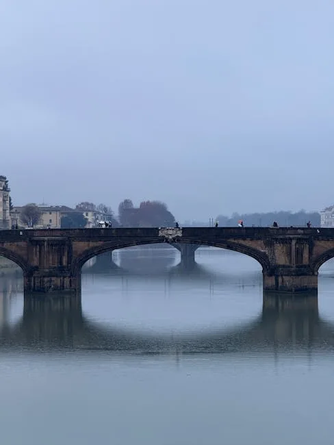 Stary most nad rzeką Arno w Pizie spowity poranną mgłą.
