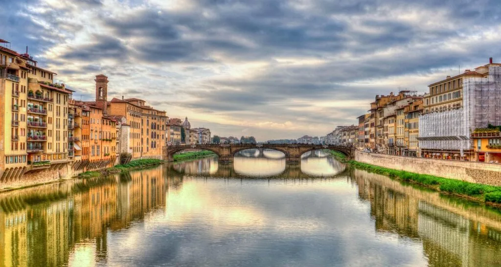 Widok rzeki Arno i Ponte Vecchio we Florencji przy zachmurzonym niebie
