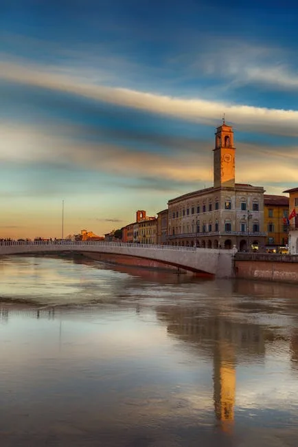 Brzeg rzeki Arno w Pizie z mostem i wieżą zegarową