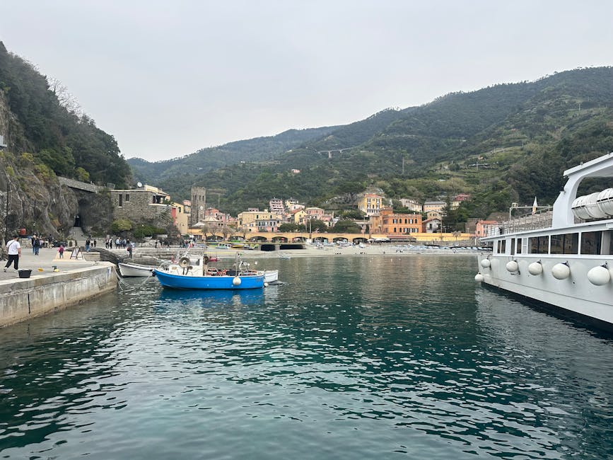Niebieska łódź w porcie Cinque Terre, wzgórza i zabudowa za nią