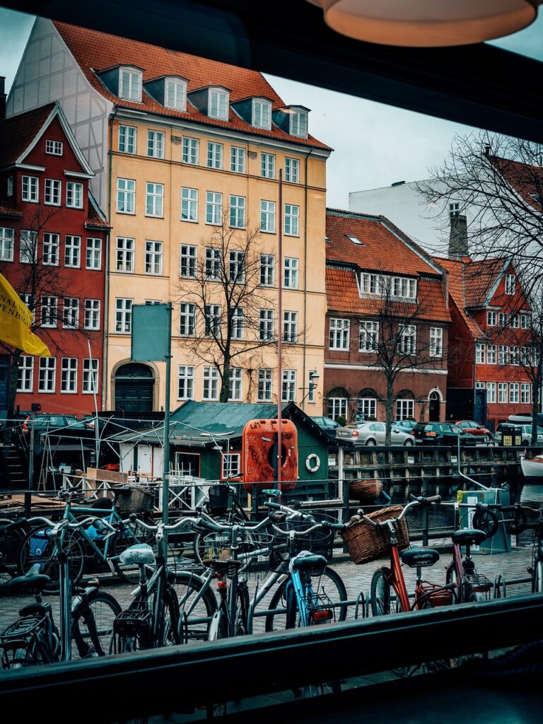 Family cycling along Christianshavn canal with colorful houses