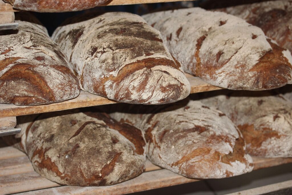 Artisan baker slicing rye sourdough bread inside a Copenhagen bakery