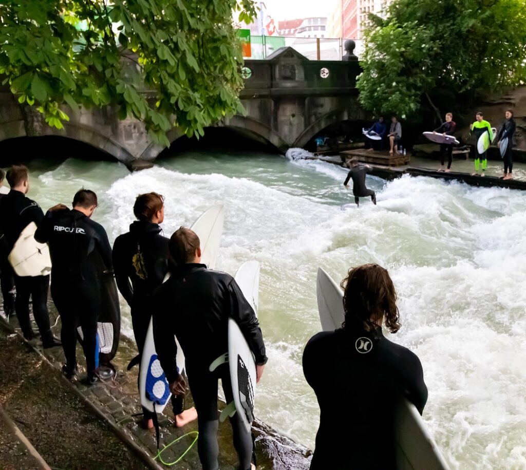 Surfers riding the Eisbach wave in the English Garden, Munich
