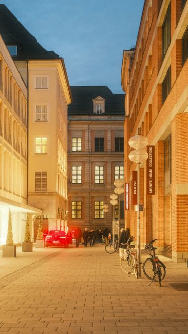 Münchner Straße mit Abendbeleuchtung und Fußgängern