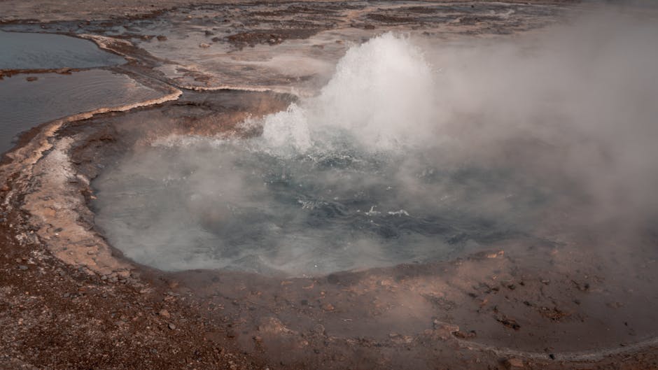 Holzsteg über bunten, brodelnden Geysir-Becken