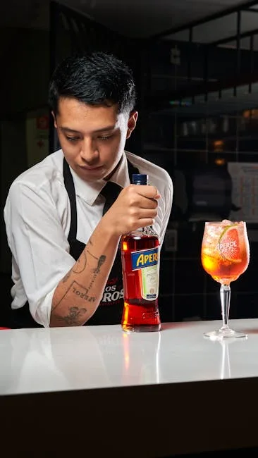 Barman tenant une bouteille d'Aperol près d'un Spritz coloré dans un bar milanais
