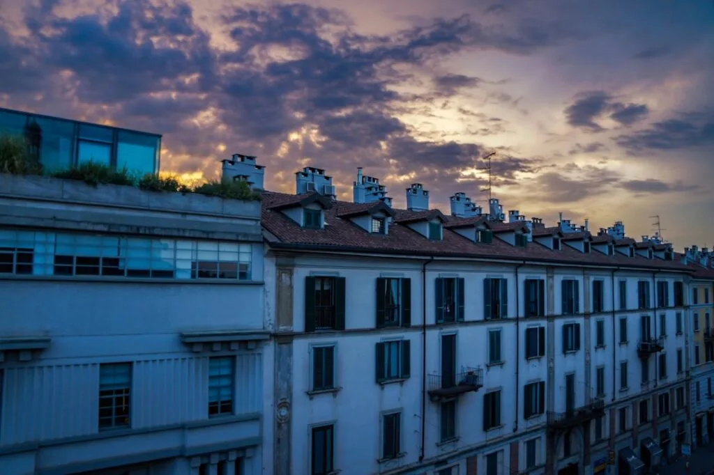 Toits d'immeubles milanais sous un ciel violet au crépuscule