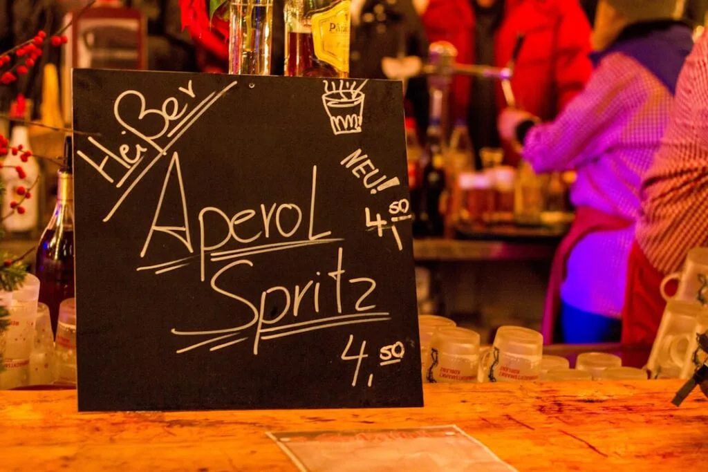 Ardoise écrite « Aperol Spritz » posée sur un comptoir animé