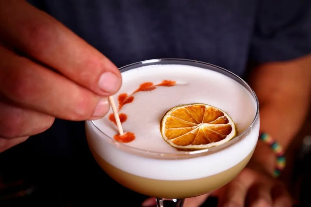 Cocktail mousseux garni d'une tranche d'agrume séchée et décor au cure-dent