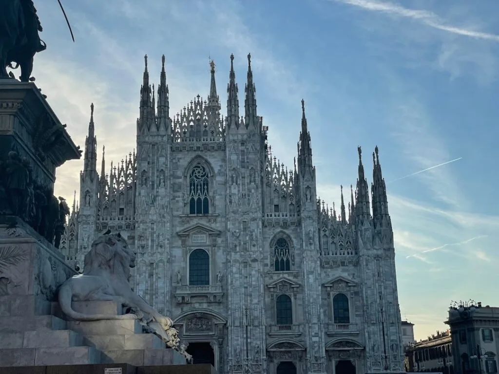 Façade gothique du Duomo de Milan avec statue de lion au premier plan