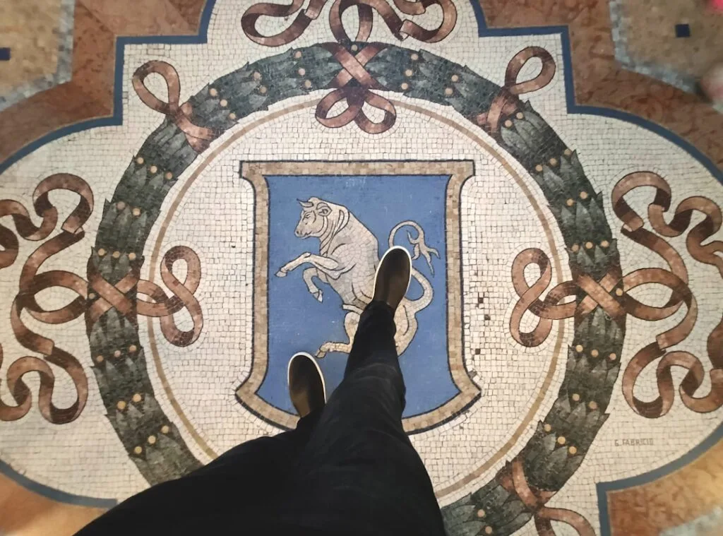 Mosaïque au sol de la Galleria à Milan représentant un taureau, pieds visibles