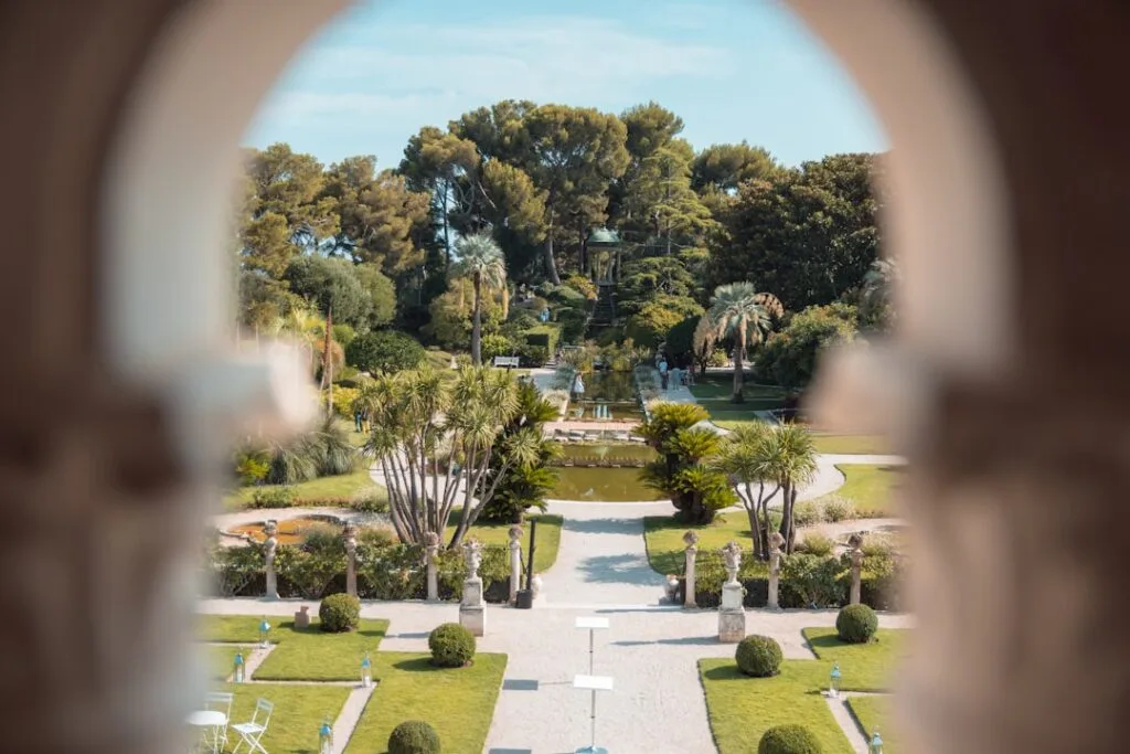 Vue cadrée par un arc sur un jardin à l'italienne près du lac.
