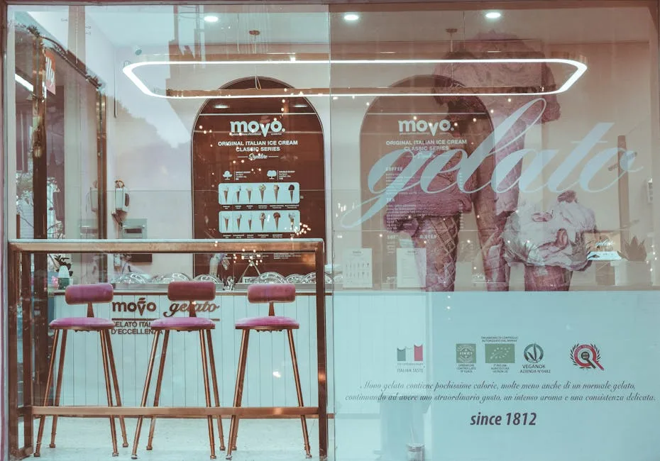 Vitrine de gelateria avec trois tabourets roses et lettrage 'movo'